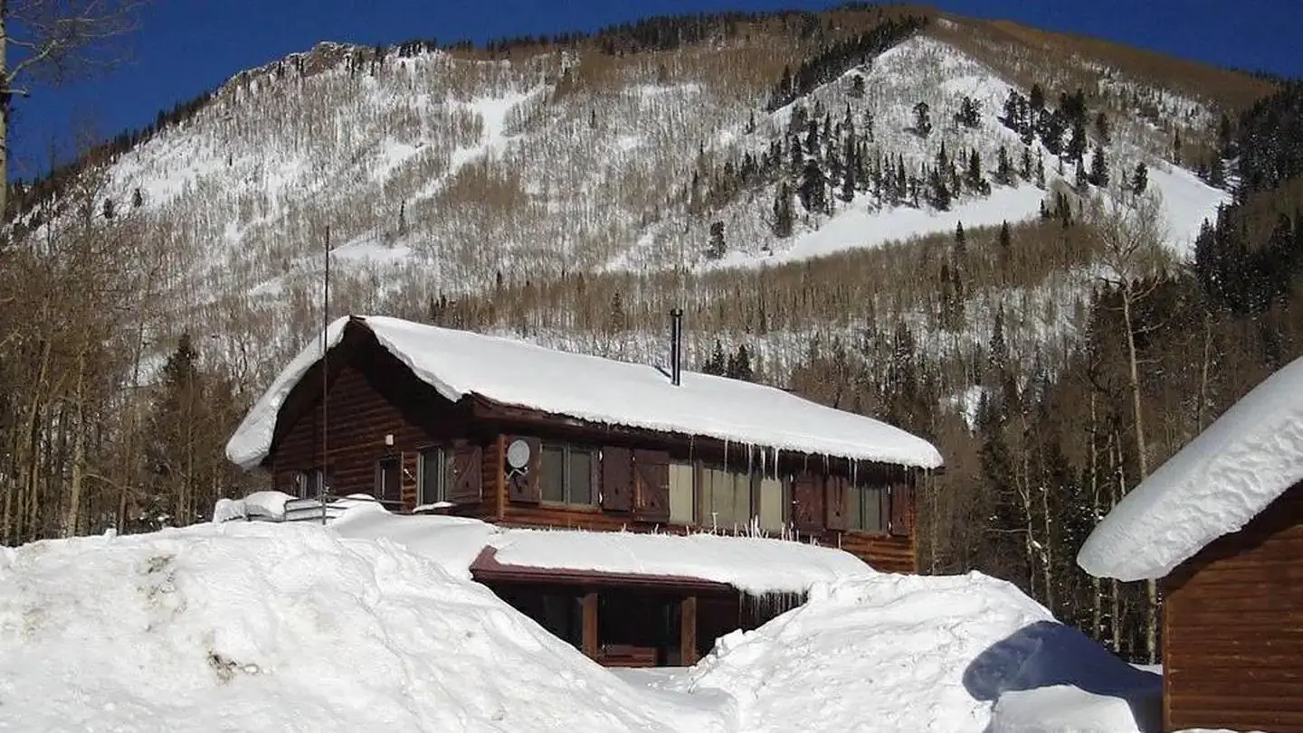 Exterior of a wood cabin covered in snow and icicles in the winter
