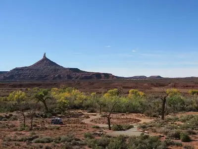 Panoramic view of the desert campground with a ribbon of cottonwood trees and Six Shooter Peak in the background.