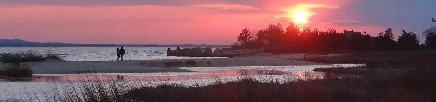 2 Park visitors walking on the beach at Horseshoe Cove while the sun is setting