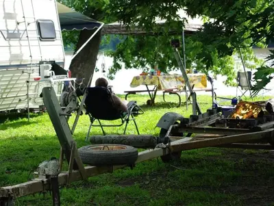 Camper looking out over the river from lawn chair and trailer