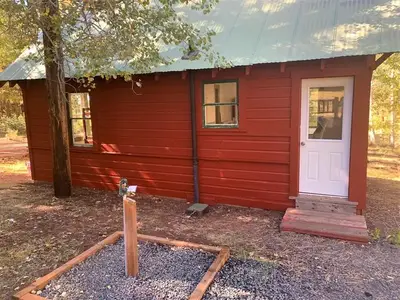 View of the rear of the guard station, facing the back door. A water faucet is in the foreground and the Aspen leaves in the background are starting to turn yellow.