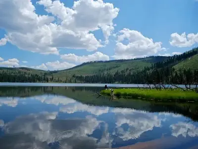 Calm water at Blue Lake clearly reflects the sky and clouds on a summer day