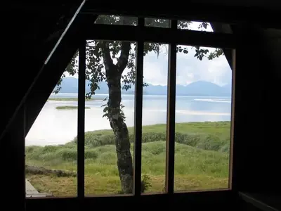 View of ocean and mountains outside Mallard Slough Cabin window