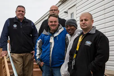 FEMA MHU Team stands on a series of platform steps for a Uniform Federal Accessibility Standard (UFAS) Manufactured Housing Unit (MHU) parked in the Prairie View campground and RV P - DPLA - 903acb334de1d49de3697c77c73f5500