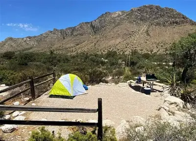 Pine Springs campground tent site.  The tent pad and picnic table are is delineated by larger rocks and fencing.  The surface is covered with find gravel. A view of Hunter Peak is in the background.