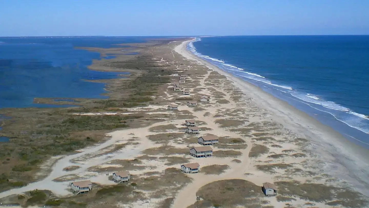 An aerial view of Great Island Cabin Camp, with the ocean on the right, the sound on the left, and the cabin area in the center