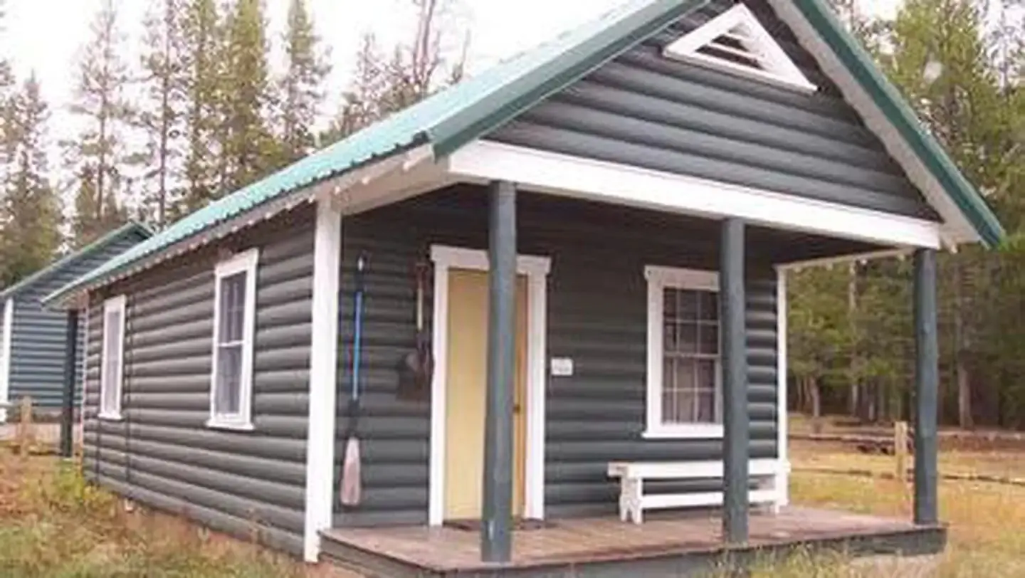 A wooden cabin with a porch in the woods