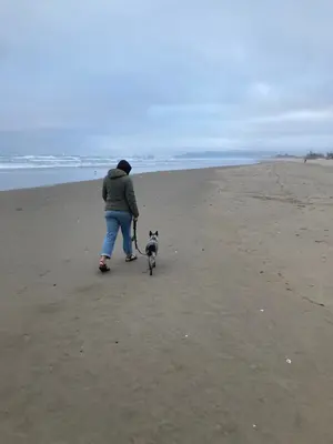 Woman and dog walk on beach at Cape Lookout State Park (Oregon)