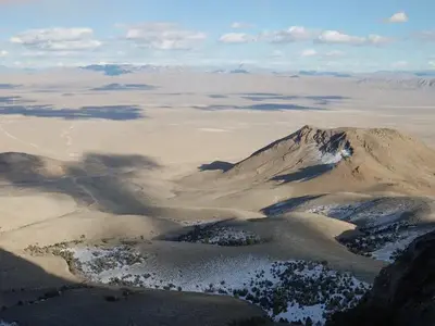 Long view of open desert with mountains and cloud shadows