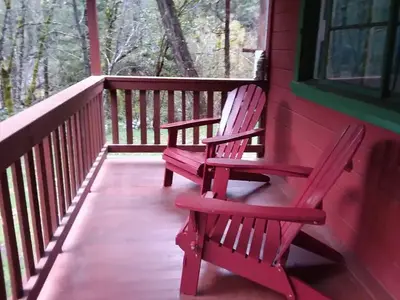 Front porch and two red Adirondack of red cabin.