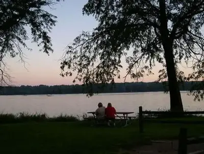 People at a picnic table at sunset overlooking the river.