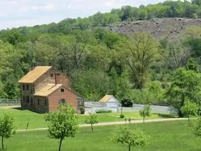 Exterior of brick house showing the slope of Little Round Top in the background