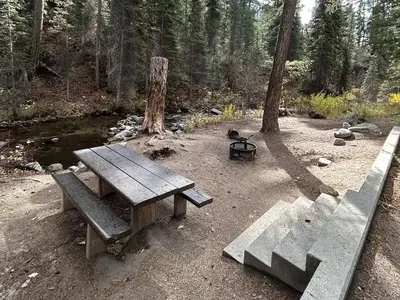 Stairs lead to creekside campsite with picnic table and fire ring.
