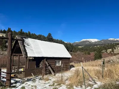 Brown cabin surrounded by green trees and rolling landscape