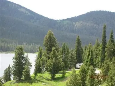 Pine trees, mountains & campsite with camper