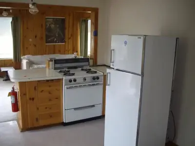 Kitched with white refridgerator and stove and wooden cabinets.