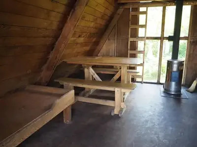 Shakes Slough 2 interior showing wood bunk, table stove and vertical ladder to loft