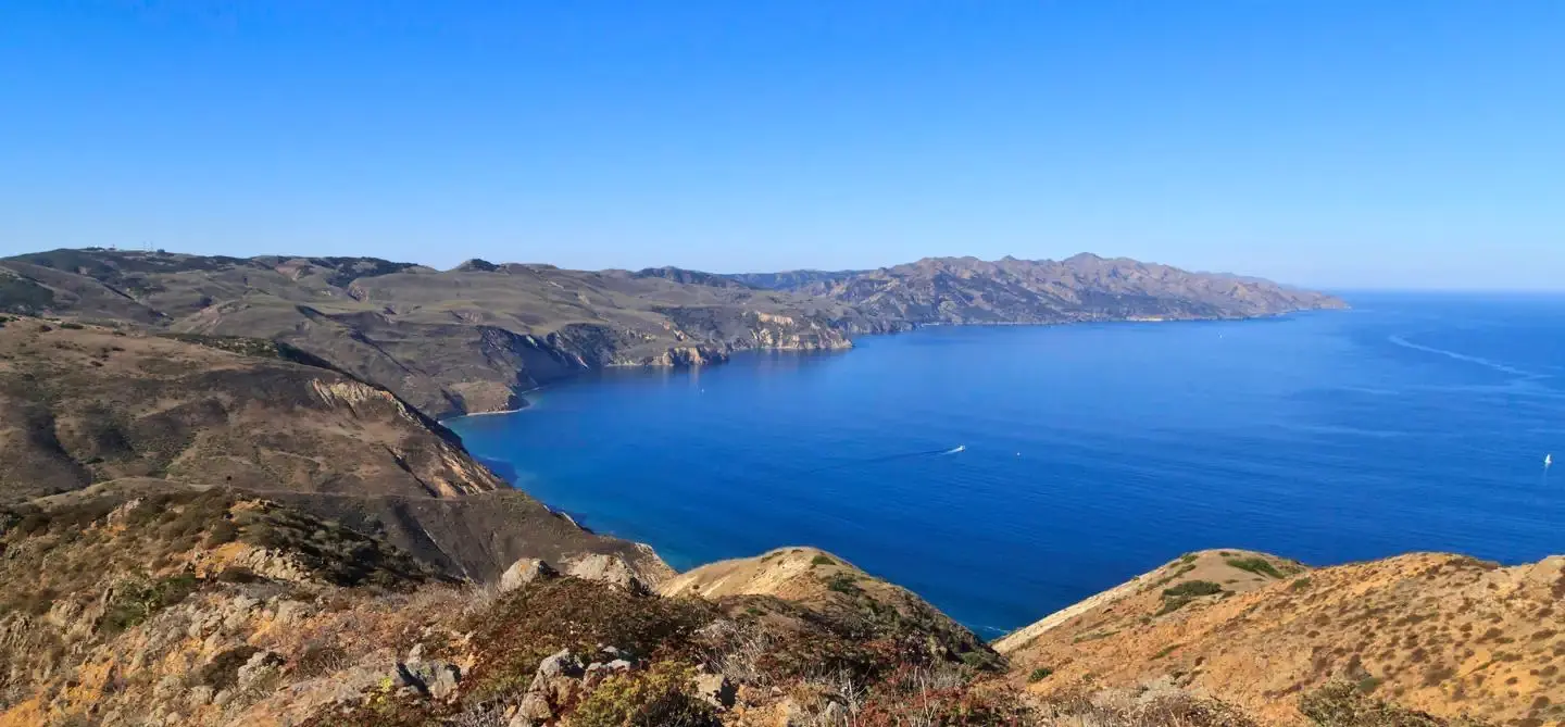 View from a high ridge overlooking the rest of a long, narrow, rugged island with steep cliffs.