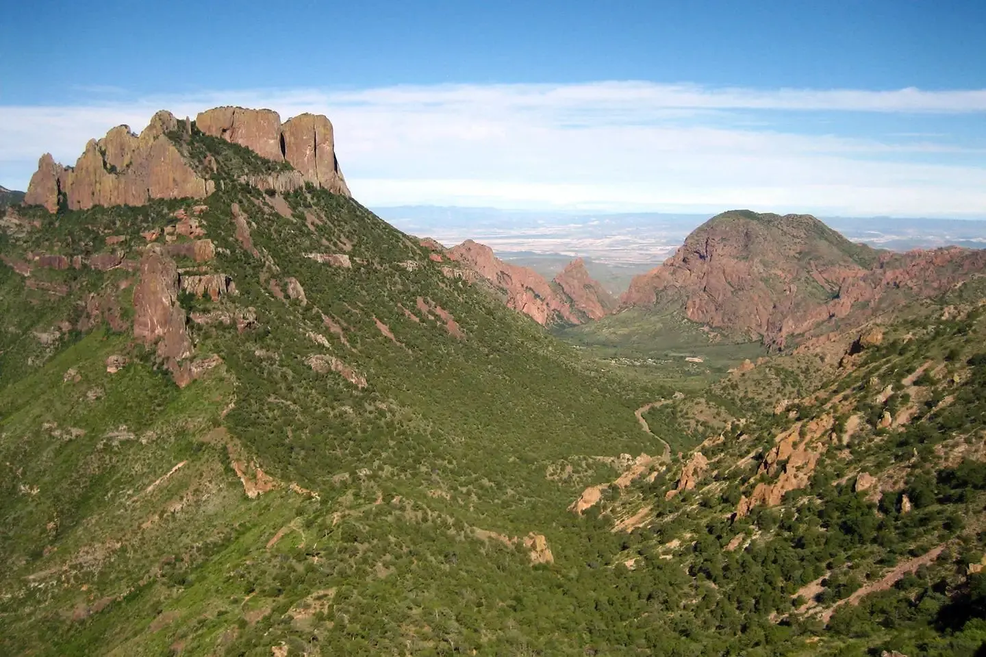 A view of Chisos Basin from the Lost Mine trail. Green vegetation with red mountains