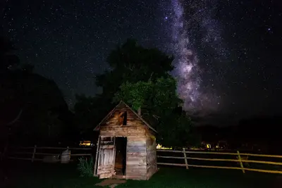 A purple starry night sky is featured behind a small building.