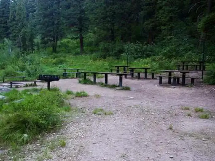 Picnic tables and benches near the raised grill and in-ground fire pit.