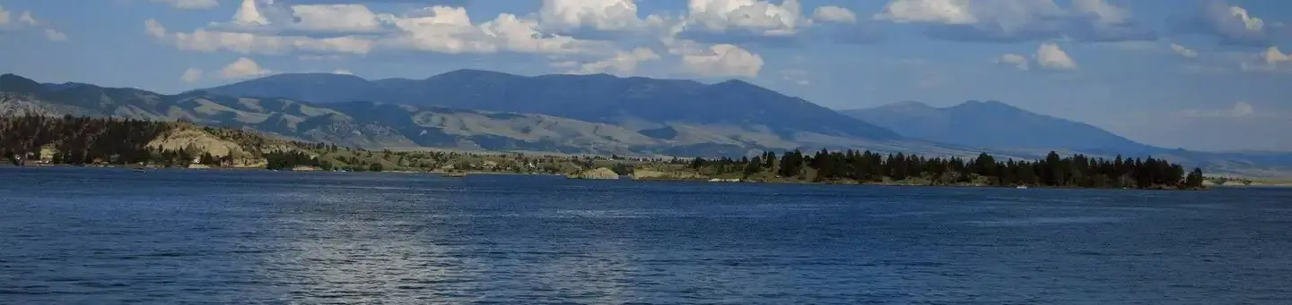Sunny lake in forefront, mountains in the background.