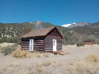 Single room cabin with two doors and an outhouse further behind