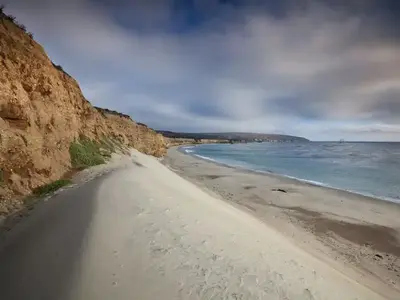 White sand dune next to a steep coastal bluff with ocean