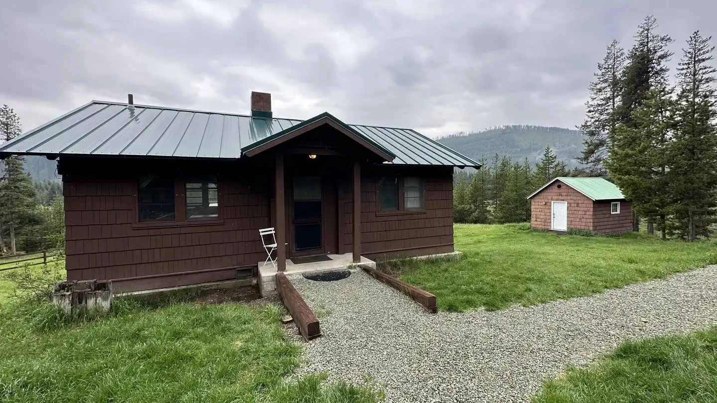 Historic forest service cabin with treed mountain behind.
