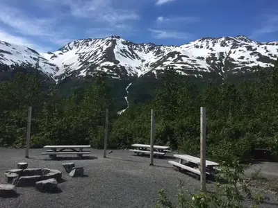 Centralized area with picnic tables, campfire ring, and poles for hanging tarps.