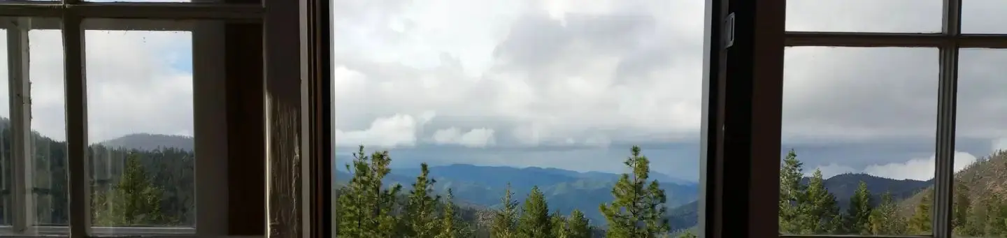 View of mountains and cloudy sky through cabin window.