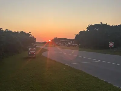 Sun rising over Ocracoke Campground capturing sunrays streaming over A Loop campsites on exterior perimeter of campground