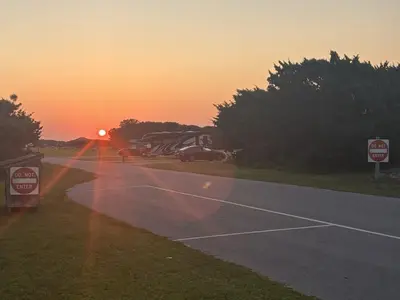 Sun rising over Ocracoke campground capturing sunrays streaming over A loop campsites on exterior perimeter of campground