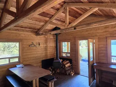 Interior of cabin with natural wood, wood stove, table and bench