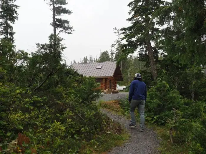 Person walking up gravel walkway to Middle Ridge Cabin with trees on both sides of him