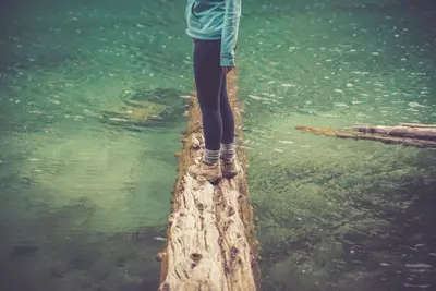 Woman on a log in a lake (Unsplash)