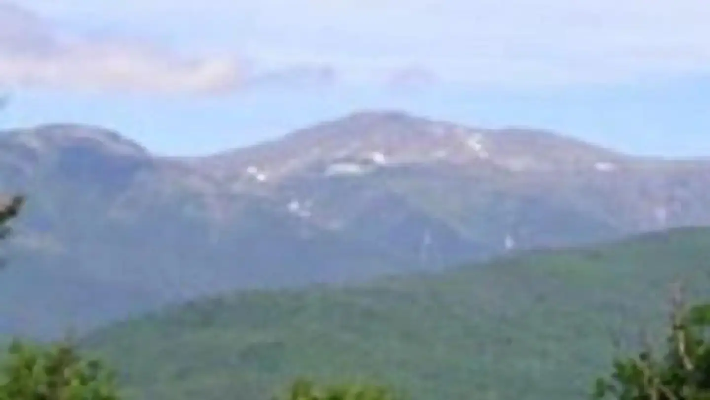 A mountain range with pockets of snow on its peaks