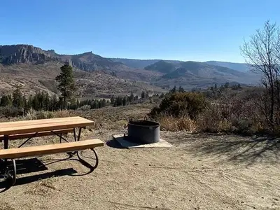 An amazing view from Ponderosa Campground showing a picnic table and firepit in the foreground