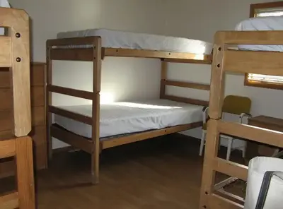 Three sets of twin wooden bunk beds with mattresses in a bedroom