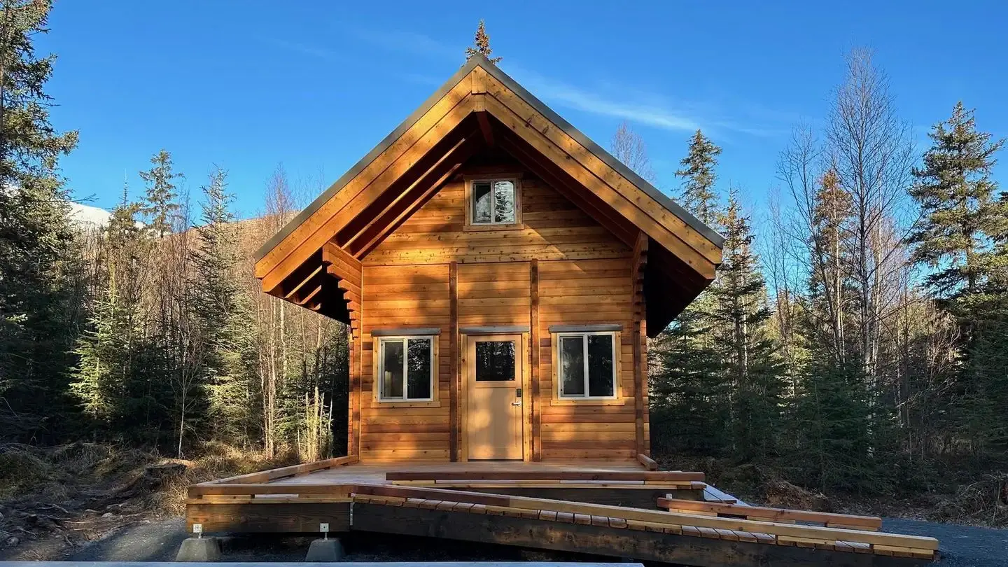Two-story log cabin with large front porch and ramp.