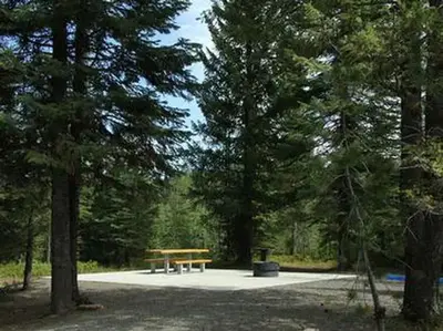 Accessible site with paved common area round fire pit, with picnic table.