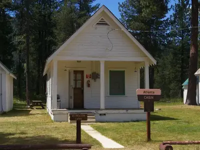 Cabins nestled in pines with most home accommodations that will sleep 4 and running hot water and picnic table, fire ring and pedestal grill behind the cabin.