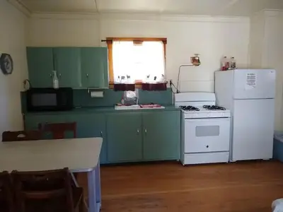 A kitchen with a table, microwave, sink, stove, and refrigerator.
