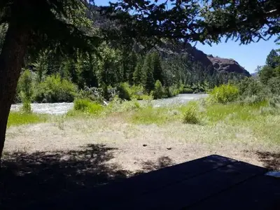 Campsite 2 with trees, river and mountains in background
