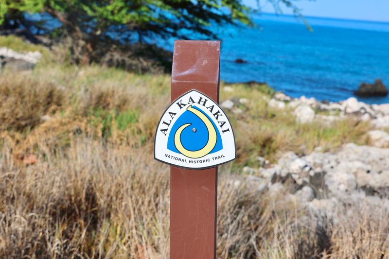 Ala Kahakai trail marker with ocean in the background