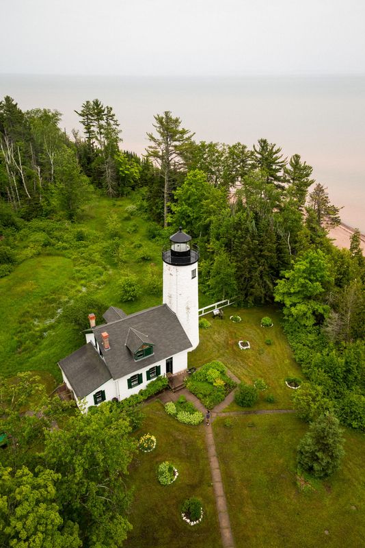Photograph of historic lighthouse from above with Lake Superior in the background.