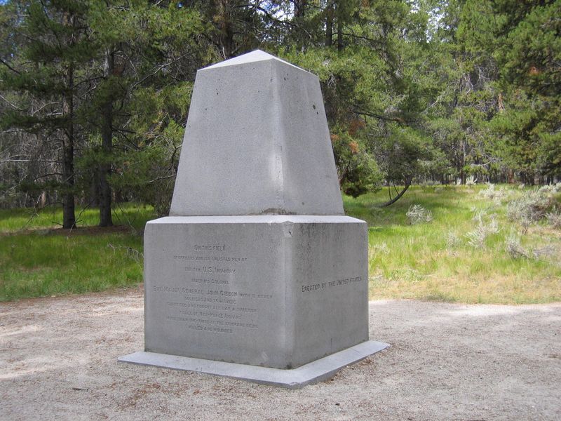 A large squared-off granite monument standing in a forest clearing