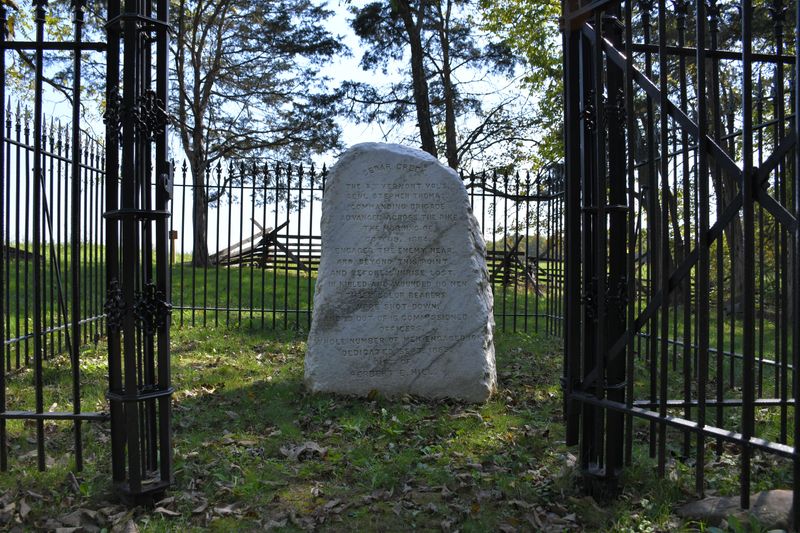 A rough marble monument in an iron-fenced enclosure commemorates Civil War combat.