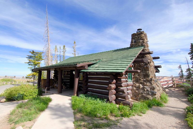 A small log cabin with a stone chimney on one side.