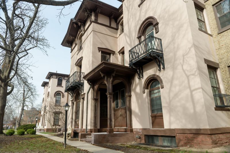 A tan and brown building, built in the Italian Villa style with rounded arches and balconies.